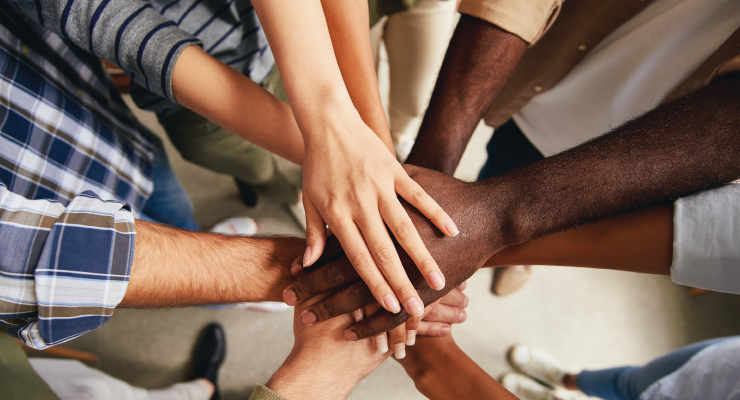 Image of hands placed in the center of a circle of people