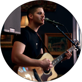 Image of man with an acoustic guitar singing into a microphone