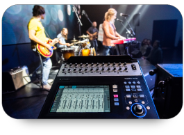 Image of a TouchMix mixer with a band in the background